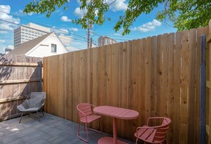 Ein Holzzaun, ein Patio-Tisch und zwei Stühle in einem Garten.
