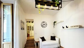 Ett modernt vardagsrum med en vit soffa, en väggklocka och en hängande lampa.