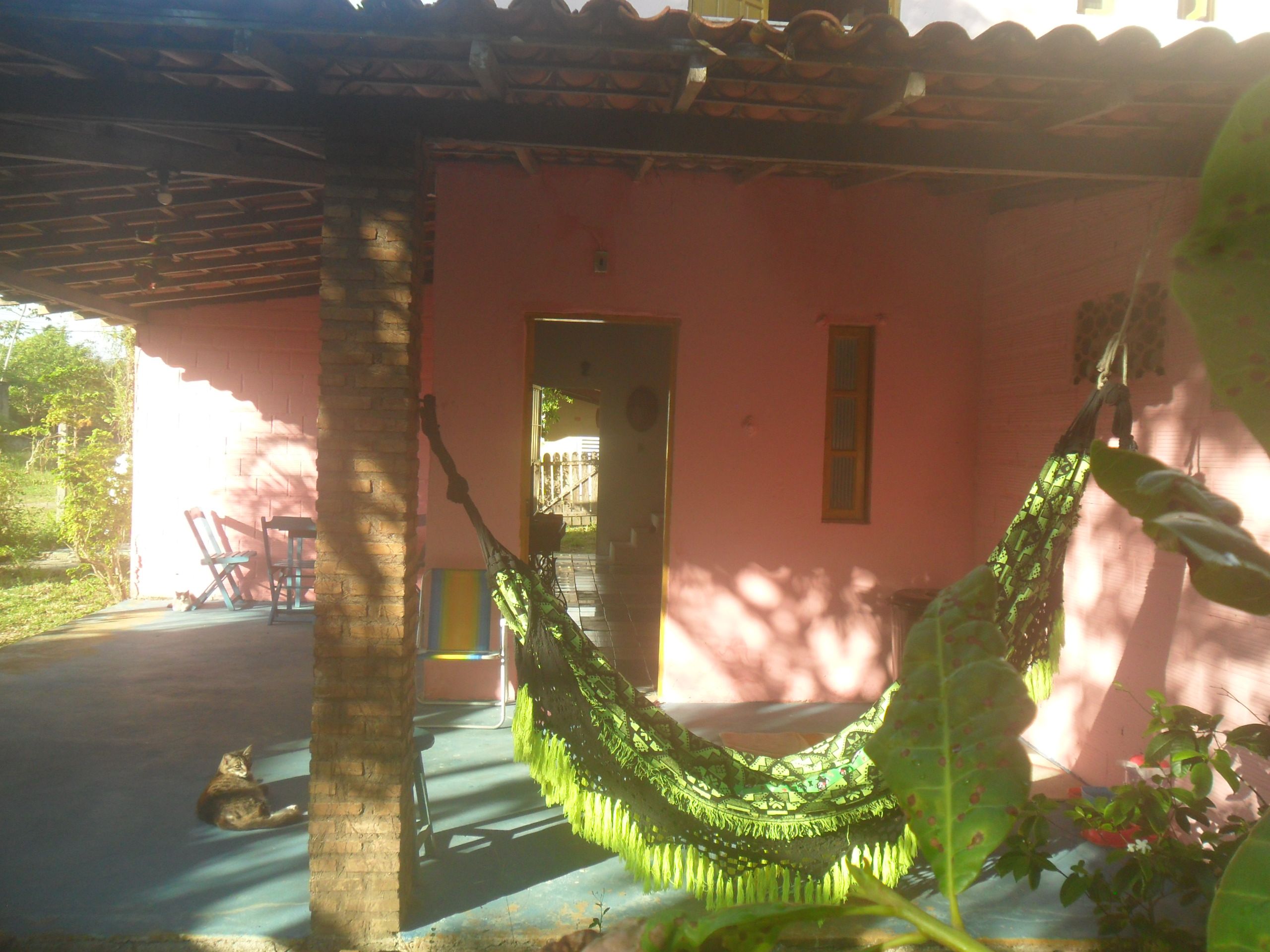 Uma rede sob um toldo com parede rosa e uma porta.