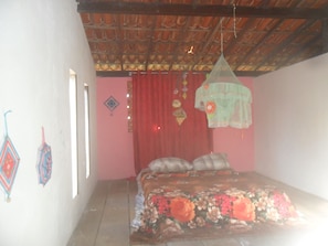 A room with a bed, a red curtain, and a hanging mosquito net.