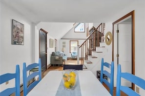 A dining area with a table, chairs, and a vase of yellow flowers.