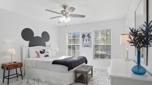 A bedroom with a bed, a nightstand, a bench, a ceiling fan, and a window with blinds.