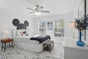 A bedroom with a bed, a nightstand, a bench, a ceiling fan, and a window with blinds.