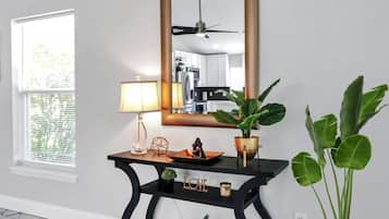 Une pièce comprenant une console, un miroir, une lampe, une plante en pot et un objet décoratif portant le mot « AMOUR ».
