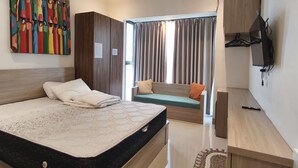 Quarto moderno com cama grande, sofá, televisão e um quadro colorido na parede.