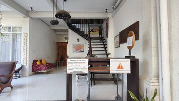 Zona de recepción con una escalera, un cartel de bienvenida y un letrero que prohíbe estacionar vehículos frente a la casa.
