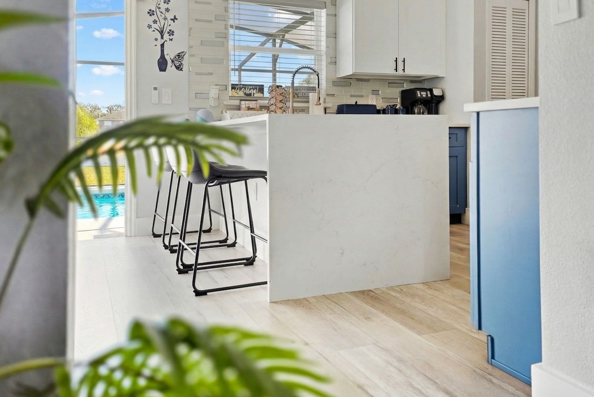 A modern kitchen with a bar area, a view of the pool, and a blue refrigerator.