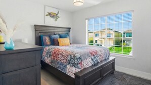 Une chambre à coucher avec un lit, une table de chevet, un vase et une fenêtre avec des stores.