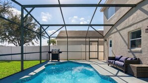 Un jardin avec une piscine, un barbecue et un espace patio couvert.