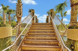 A wooden staircase with a rope barrier, surrounded by palm trees. - King Bed | Disney Contemporary Townhouse (Kissimmee)