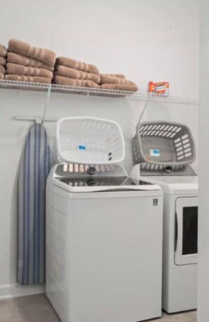 A laundry area with a washing machine, dryer, and stacked towels on a shelf. - King Bed | Disney Contemporary Townhouse (Kissimmee)