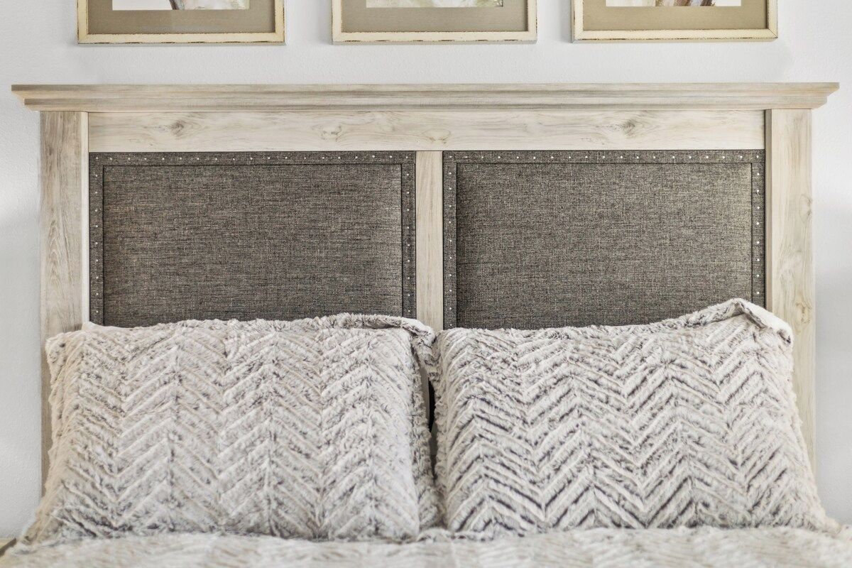 A bed with a wooden headboard and two pillows.