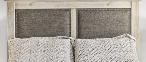 Ein Bett mit einem hölzernen Kopfteil und zwei Kissen.