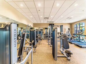 Une salle de sport équipée de divers appareils d’exercice, notamment des machines de musculation et des tapis de course.