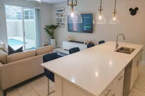 Een moderne keuken met een groot kookeiland, een zithoek met een bank en een aan de muur bevestigde televisie.