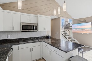 A modern kitchen with white cabinets, a stainless steel microwave, and a granite countertop. - Lakefront Paradise with 4 Decks and Unmatched Panoramic Views! (Sunrise Beach)
