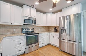 A modern kitchen with white cabinets, stainless steel appliances, and a wooden floor. - Perfect 4-bedroom house with AC on tranquil Bridgeport Lake with dock (Chico)
