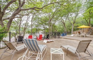 An outdoor seating area with lounge chairs and tables, surrounded by trees and a view of a body of water. - Perfect 4-bedroom house with AC on tranquil Bridgeport Lake with dock (Chico)