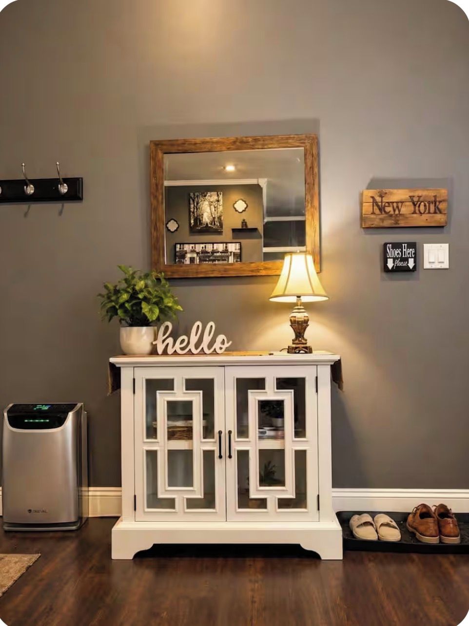 Ein Zimmer mit einem weißen Schrank, einem Spiegel, einem Schild mit der Aufschrift 'hello' und einer Lampe. An der Wand befindet sich ein Schild mit 'New York'.