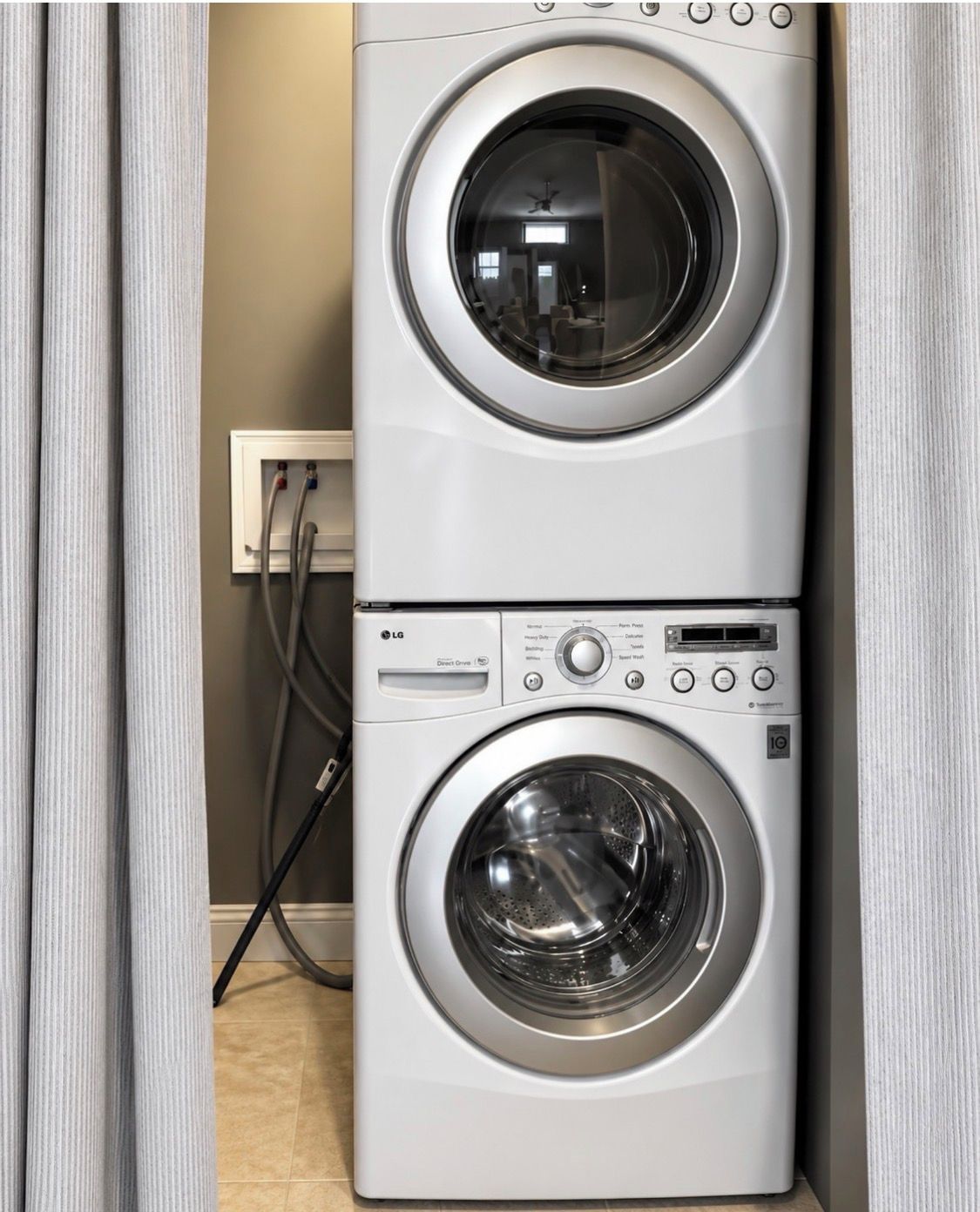 A stacked washer and dryer unit with a control panel, power cord, and a wall outlet.