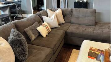 A living room with a sectional sofa, a coffee table, and a dining area with a table and chairs.