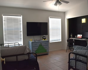 Ein Schlafzimmer mit einem Bett, einem Schreibtisch mit Computer, einem Fernseher und einer Kommode im Minecraft-Design.