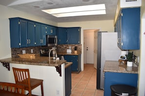 Eine Küche mit blauen Schränken, einer Arbeitsplatte aus Granit und einem Edelstahl-Kühlschrank.