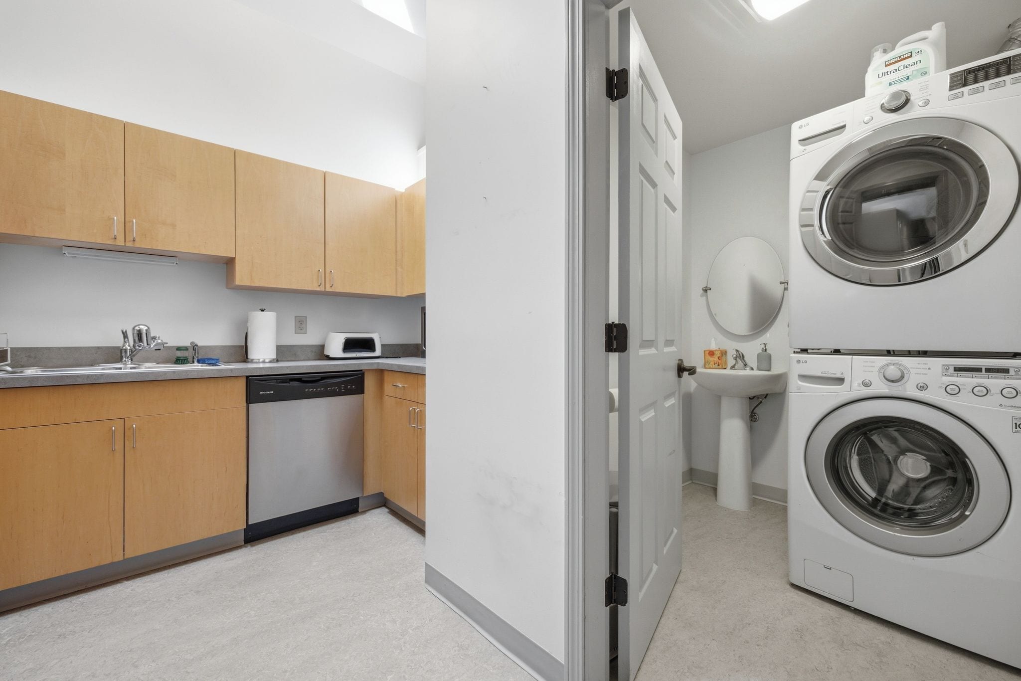 A compact kitchen with wooden cabinets, a dishwasher, a microwave, and a double washing machine.