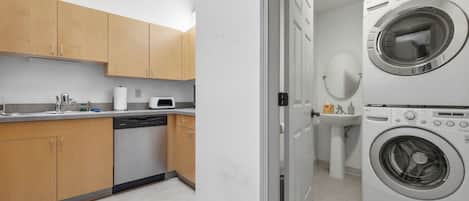 A compact kitchen with wooden cabinets, a dishwasher, a microwave, and a double washing machine.