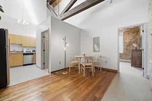 A modern kitchen with wooden cabinets, a dining area with a round table and chairs, and a brick wall.