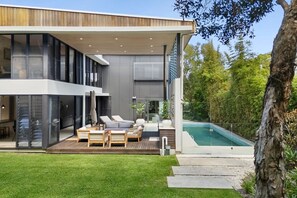 A modern house with a pool, outdoor seating, and a well-maintained lawn.