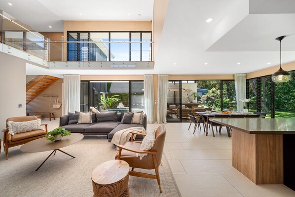 A spacious living area with a high ceiling, a dining area, and a kitchen with a large island.