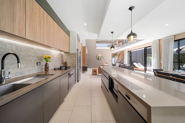 A modern kitchen with a central island, stainless steel appliances, and a view to a balcony.