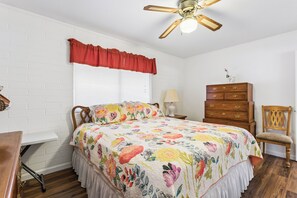 Un dormitorio con cama, cómoda, silla y ventilador de techo.