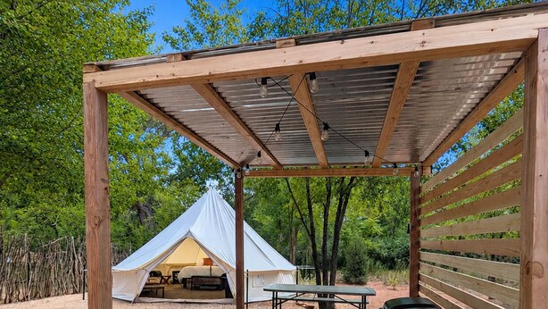 A covered picnic area with a tent, picnic table, and grill. - The Palisade Tent at Gateway Glamping (Gateway)