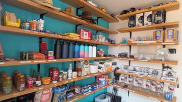 Une pièce de rangement avec des étagères contenant divers articles, comme des bouteilles, des boîtes de conserve et des cartons.