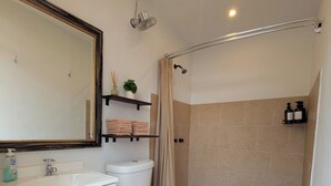 A bathroom with a toilet, sink, mirror, shower, and towel rack. - The Palisade Tent at Gateway Glamping (Gateway)