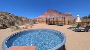 A swimming pool with lounge chairs and a wooden deck, surrounded by a fenced area with a mountain in the background. - The Palisade Tent at Gateway Glamping (Gateway)
