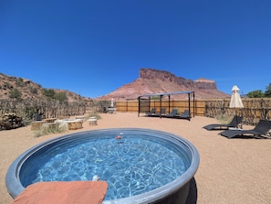 Une piscine dotée de chaises longues et d’une terrasse en bois, entourée d’un espace clos avec une montagne en arrière-plan.