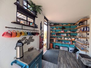 Cocina compacta con estación de café, repisas con diversos artículos y vista al exterior.