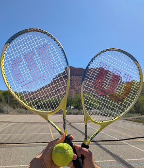 Una persona sosteniendo dos raquetas de tenis y una pelota.