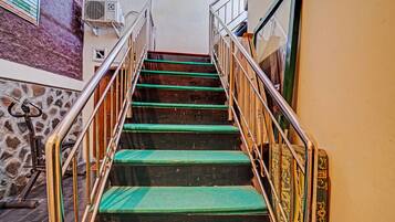 Una escalera con peldaños alfombrados de verde y barandillas de metal, que conduce a un piso superior.