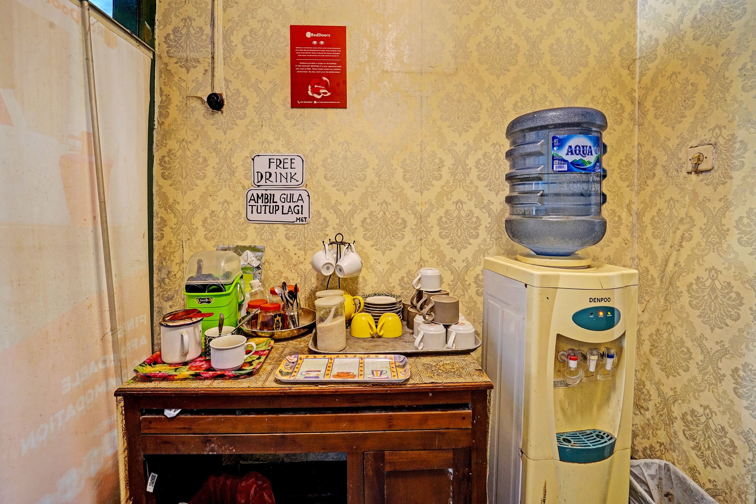 Una kitchenette con dispensador de agua, cafetera y un cartel que ofrece bebidas gratuitas.