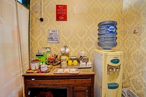 Une petite cuisine équipée d’un distributeur d’eau, d’une machine à café et d’un panneau indiquant que des boissons sont offertes gratuitement.