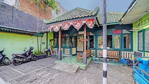 Un edificio tradicional con techo de tejas, un cartel que indica que hay una habitación disponible y una motocicleta estacionada afuera.