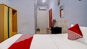 Una habitación de hotel con una cama, un armario de madera, un escritorio y una silla.