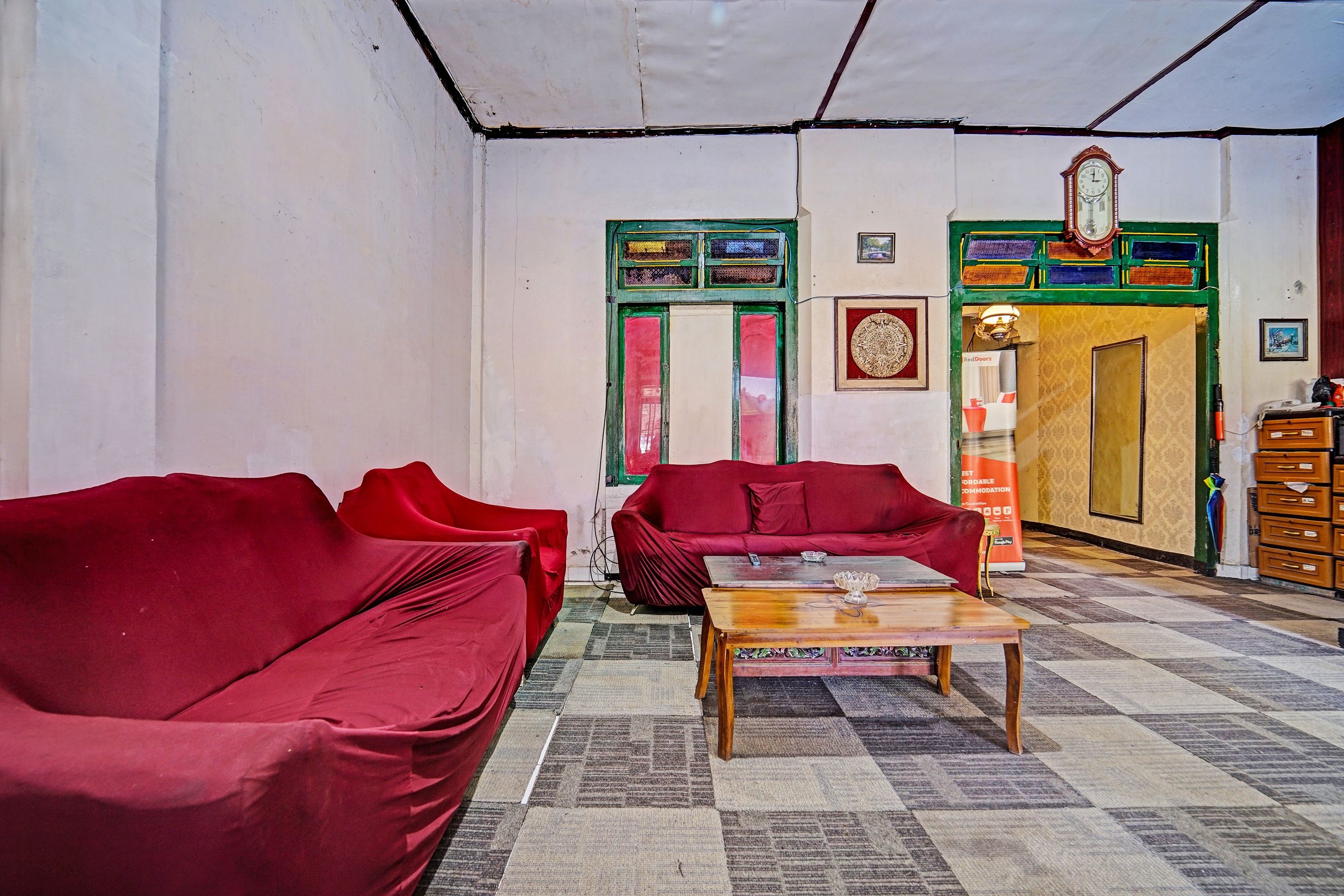 A room with two red sofas, a wooden coffee table, and a patterned carpet.