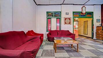 A room with two red sofas, a wooden coffee table, and a patterned carpet.