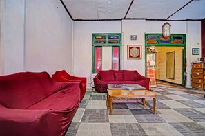 Una habitación con dos sofás rojos, una mesa de centro de madera y una alfombra estampada.
