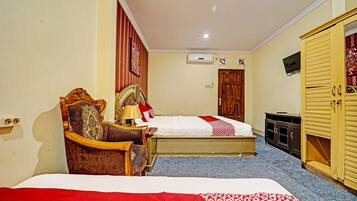 Una habitación de hotel con cama, una silla, televisor y armario.
